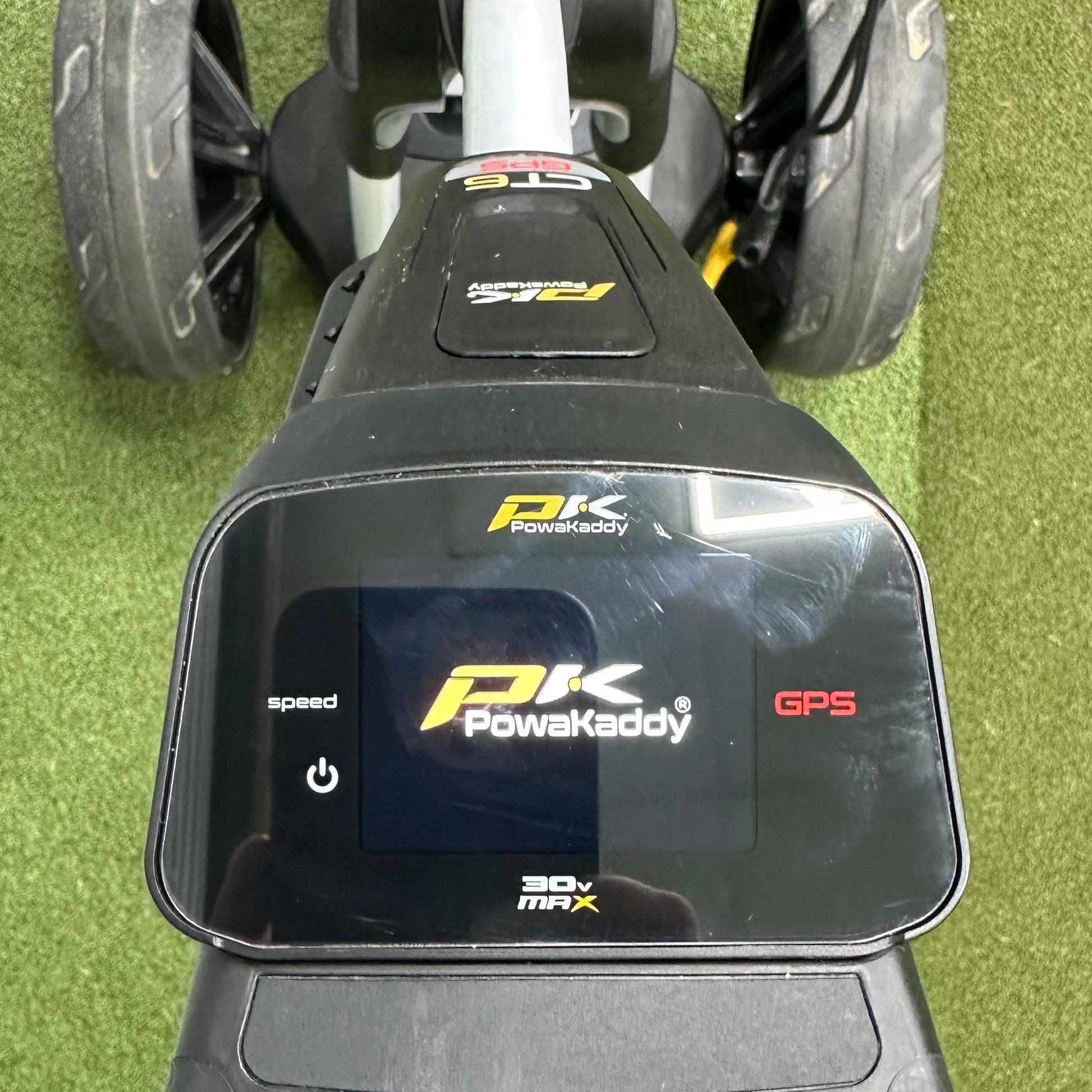 Close-up of a PowaKaddy GPS device on a golf cart, with grass in the background.